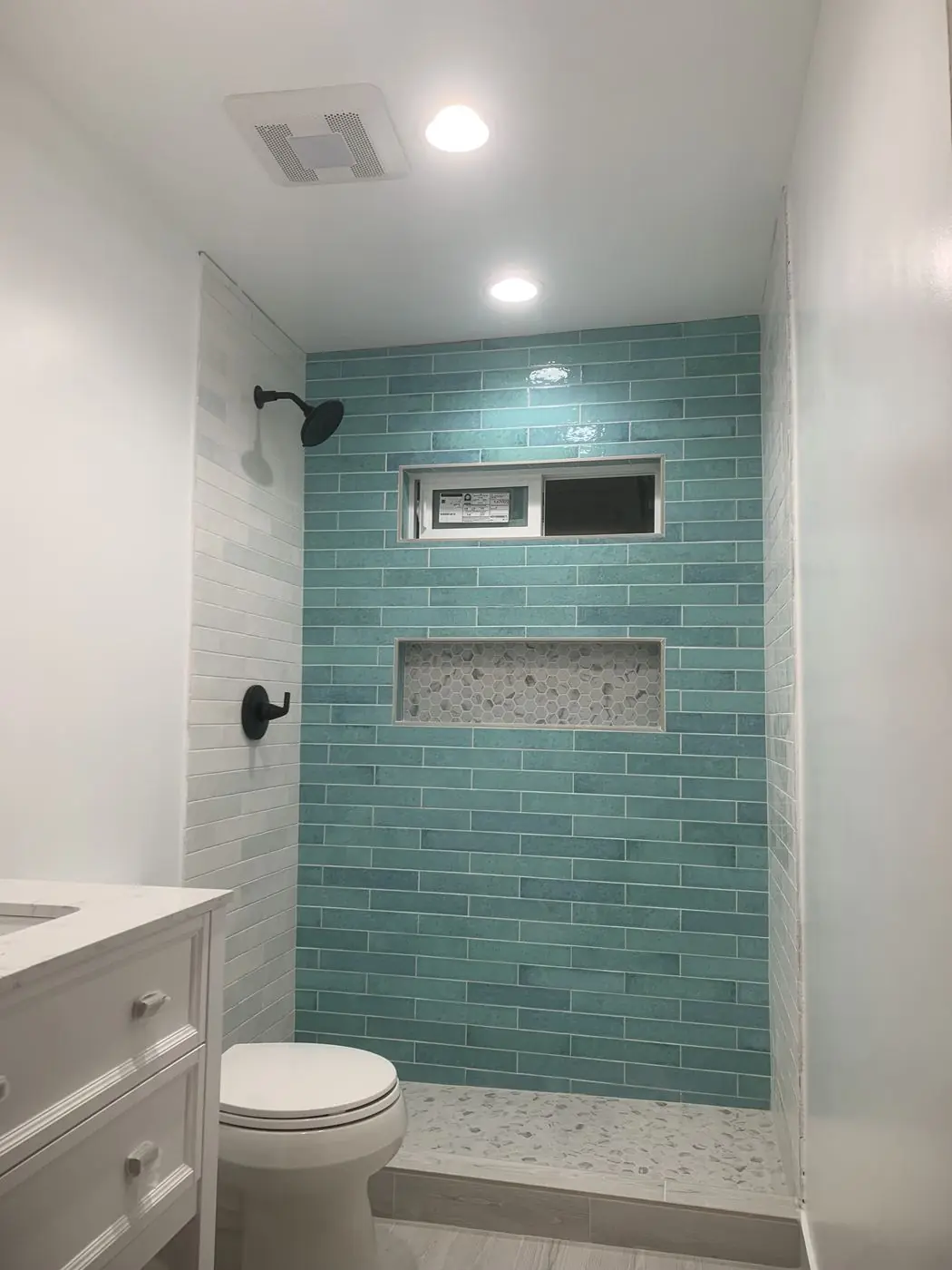 Teal subway tile shower with niche